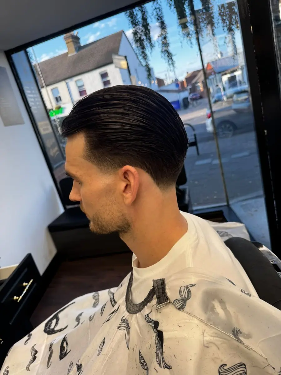 Dark slick-back with tapered sides cut at Noah's Barber West Wickham